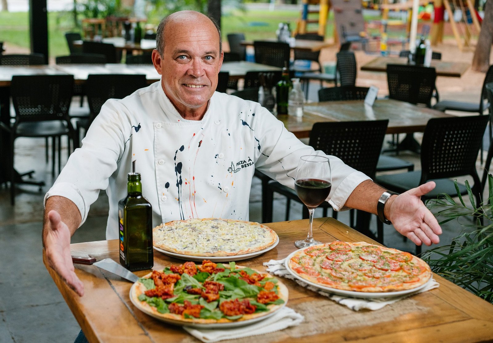 Paulo Bessa, fundador da Pizza à Bessa, à mesa com duas pizzas